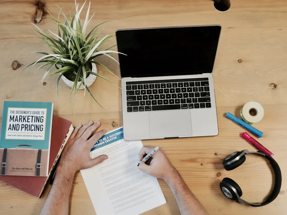 Desk with a marketing book, laptop, and notebook